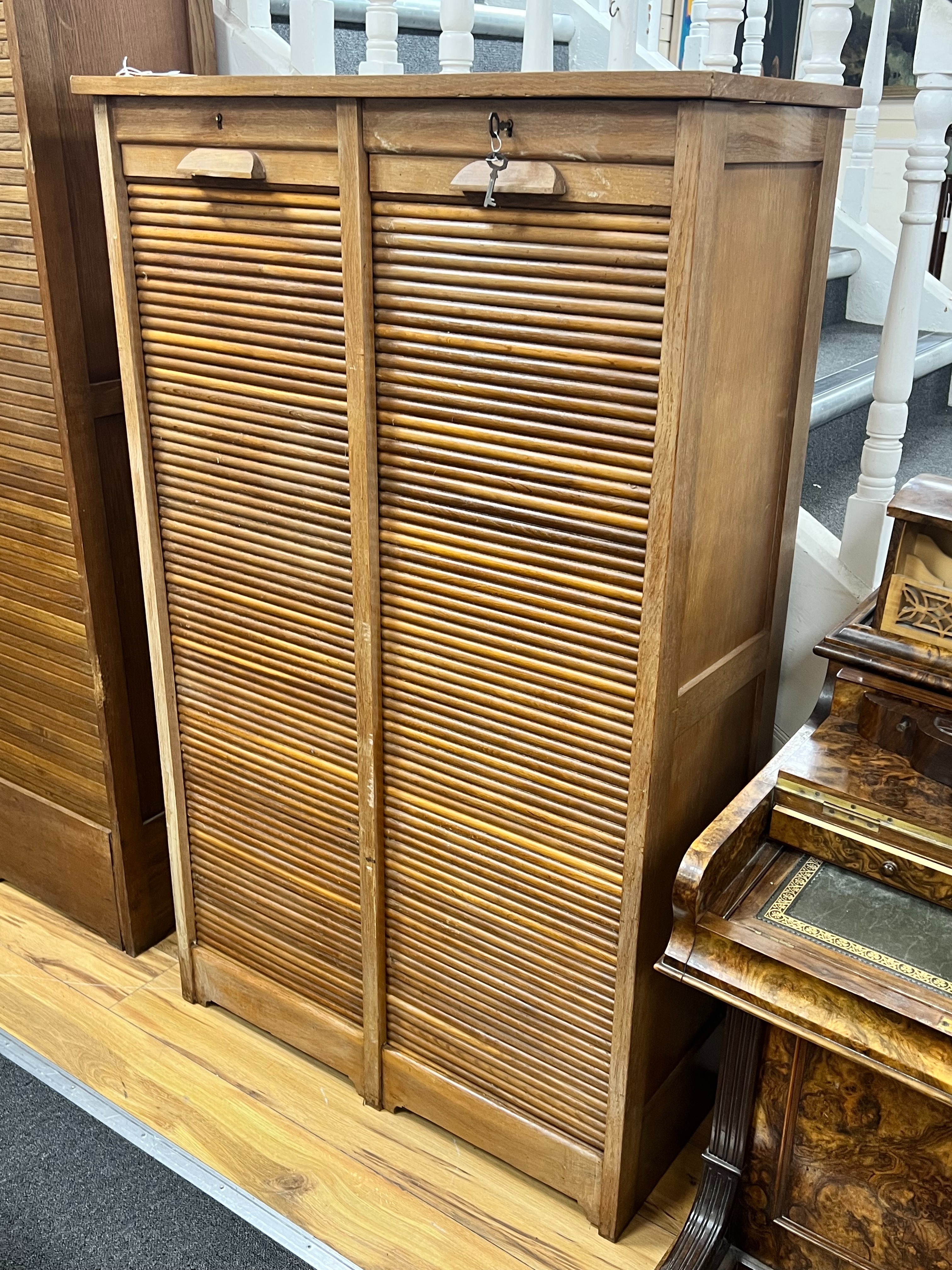 A mid century oak double tambour filing cabinet, width 87cm depth 38cm height 143cm